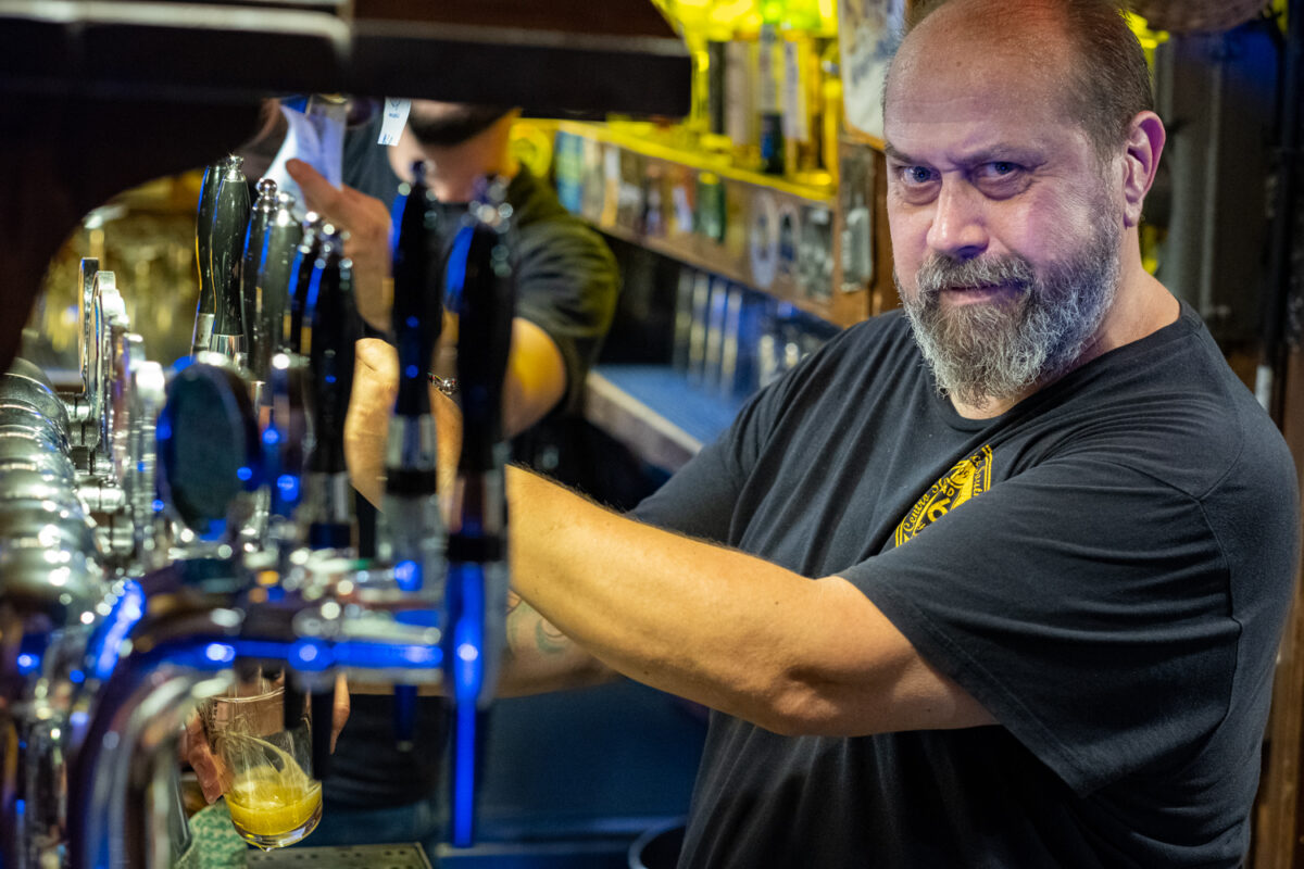 Un barista del Road 66 spilla una birra chiara alle pompe illuminate di blu, dietro il bancone